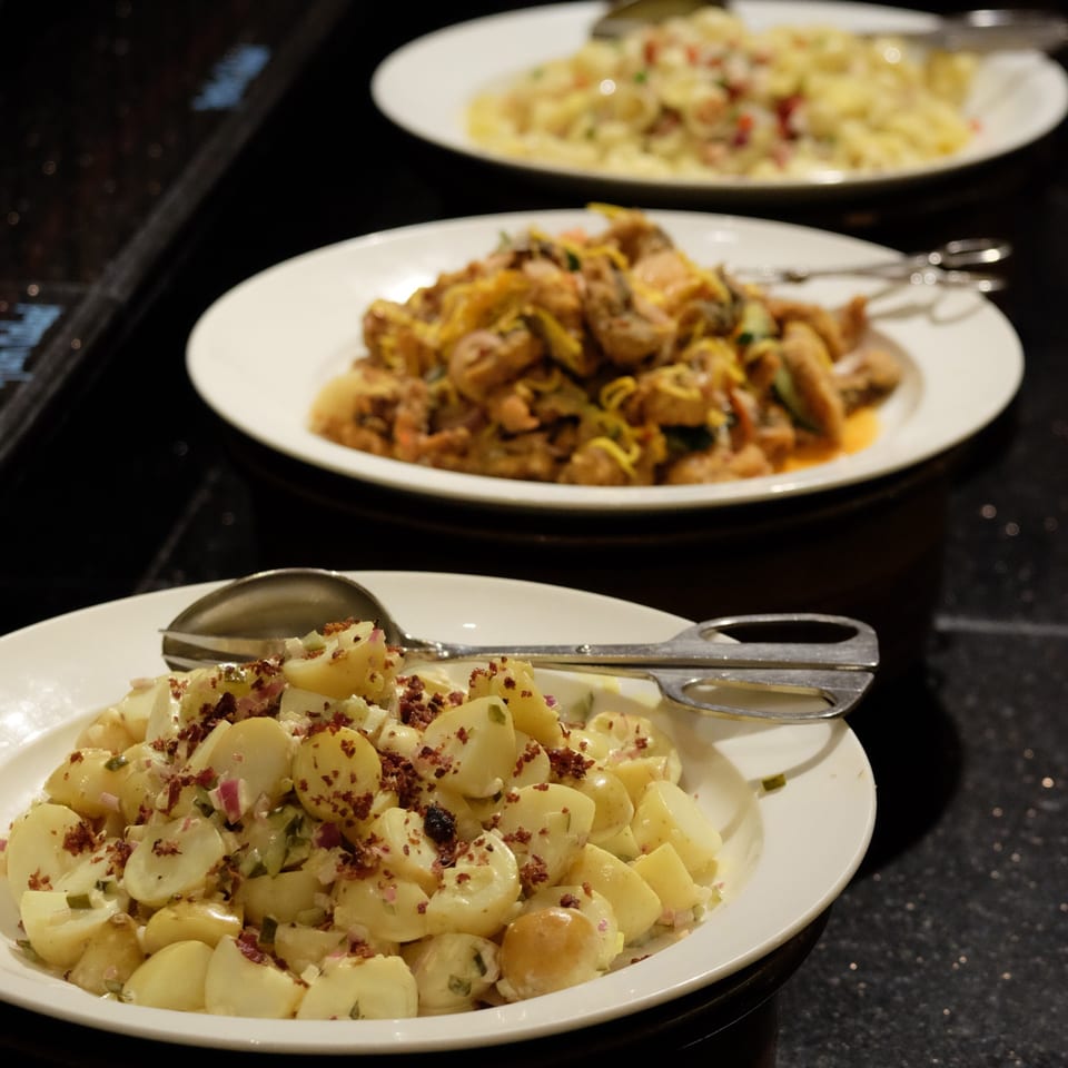 Three plates of Italian dishes, including potato salad, pasta with chicken, and creamy pasta.