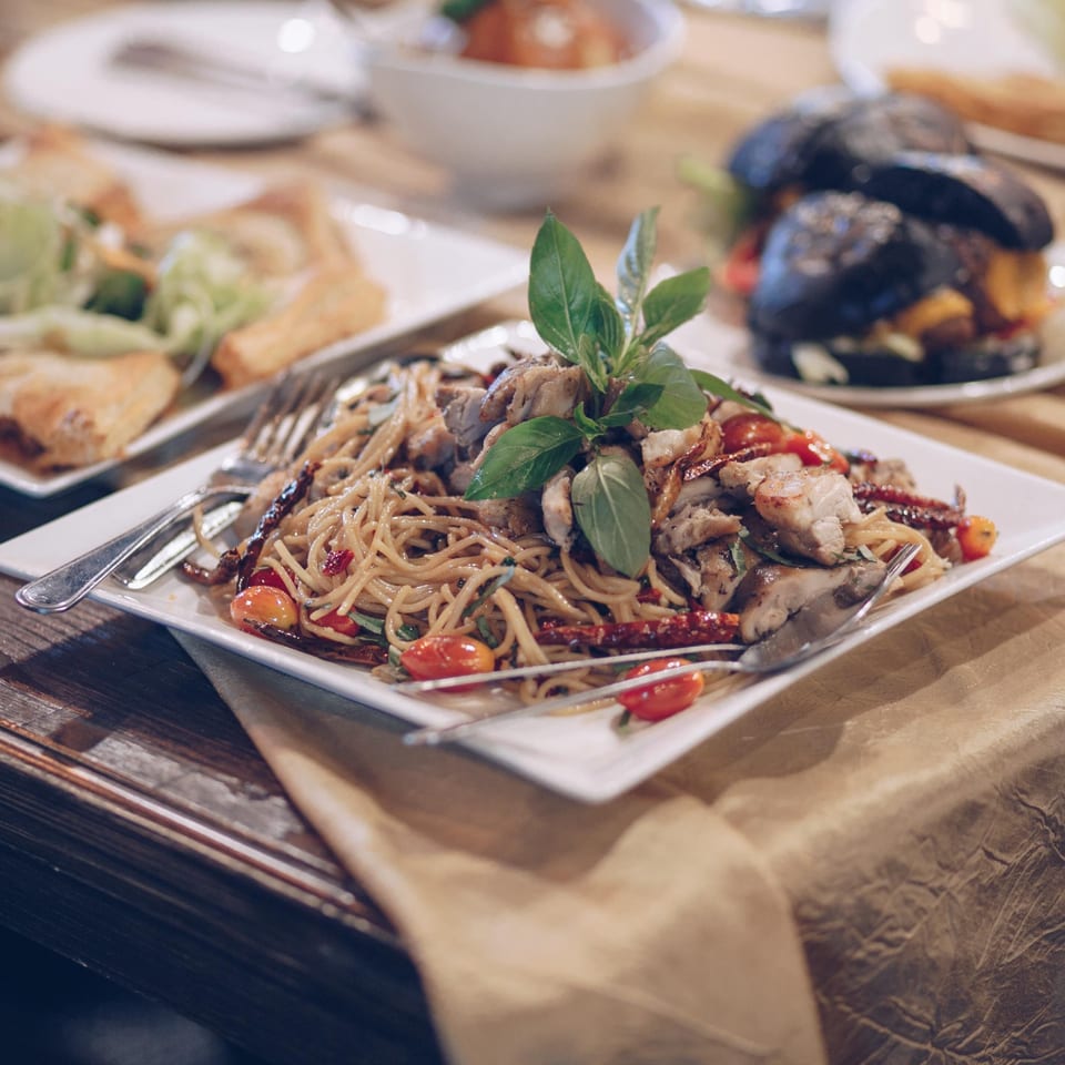 Spaghetti with chicken, cherry tomatoes, and basil on a white plate at Vino Cappuccino.
