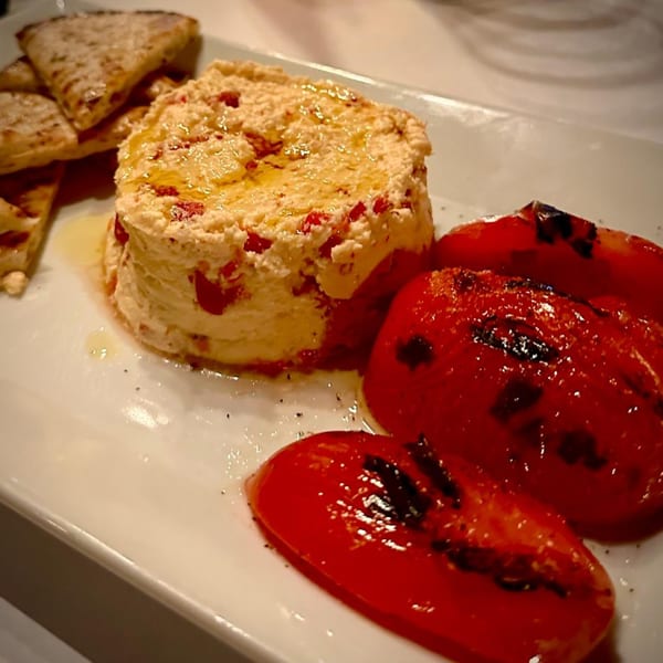 Italian appetizer with whipped ricotta, roasted red peppers, and toasted flatbread on a white plate.