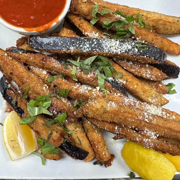 Crispy fried eggplant fries with parmesan, fresh basil, lemon wedges, and a side of marinara sauce.